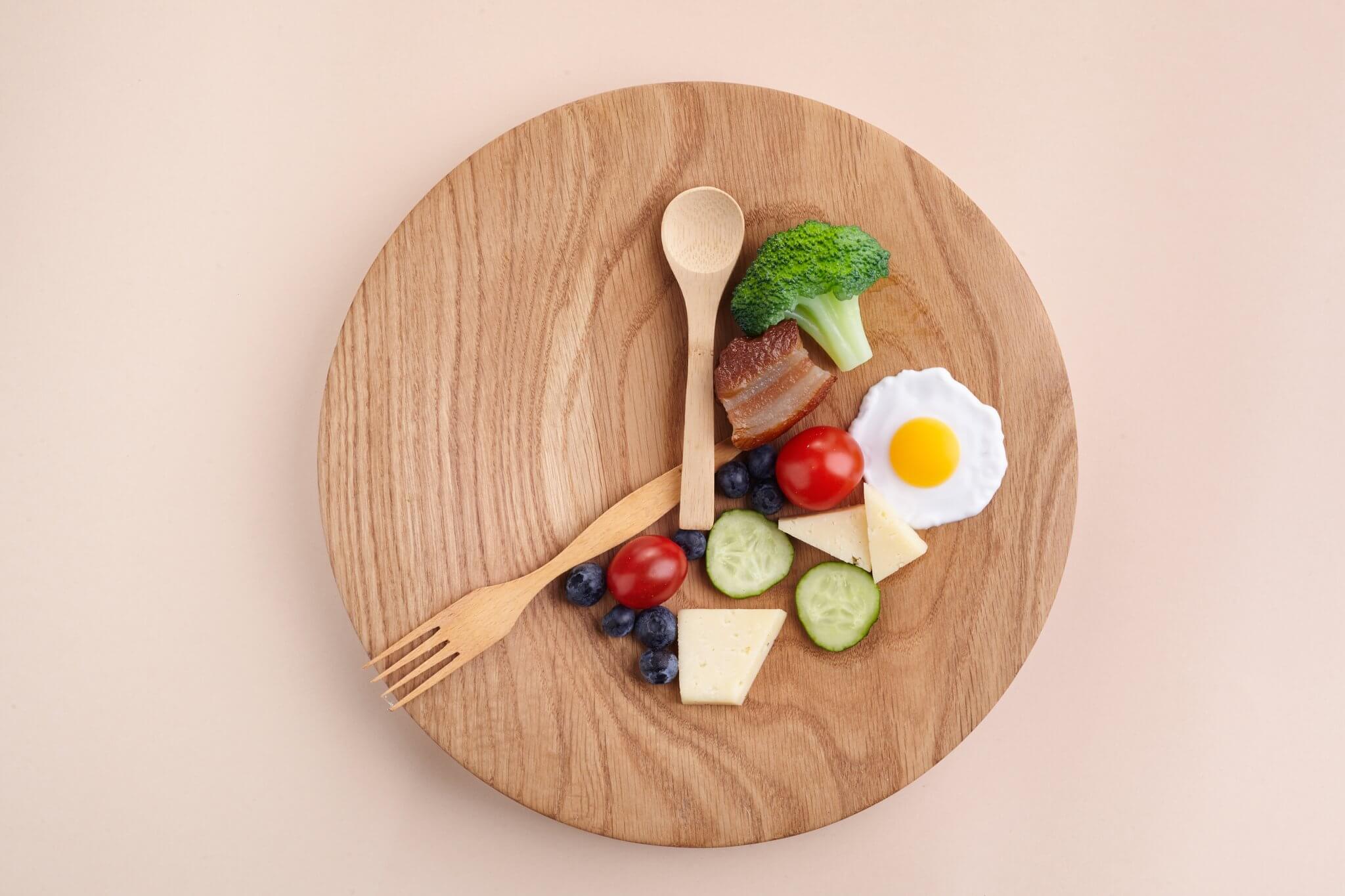wood plate of food in teh shape of a clock for intermittent fasting