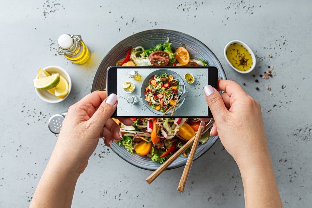 plate of salad with someone taking a photo of it for social media
